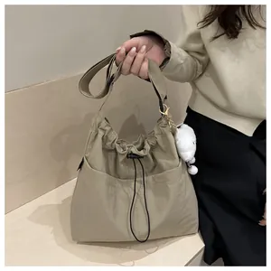 Detail of khaki drawstring crossbody bag with plush puppy charm and minimalist design