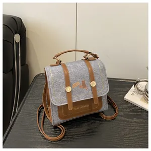 Detail of vintage square bag showing blue denim texture with brown leather accents