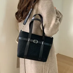 Detail of vintage black bucket bag with buckle belt on wool texture fabric
