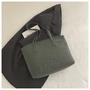 Top-down view of dark green leopard tote bag on a blazer with elegant suede texture