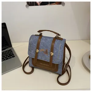 Detail of blue denim and brown leather backpack with cat illustration and gold buckle