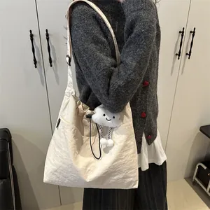 Minimalist cream white nylon tote bag with drawstring closure and cloud plush charm