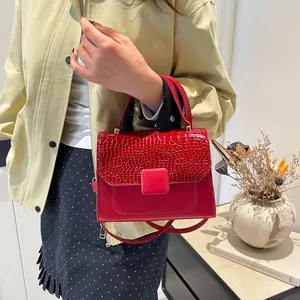 Elegant red crocodile texture handbag with shoulder strap shown in a modern lifestyle setting