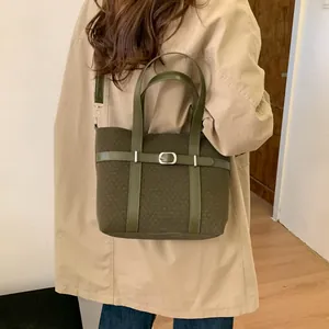 Detail of dark green jacquard bucket bag with leather strap and metal buckle accent