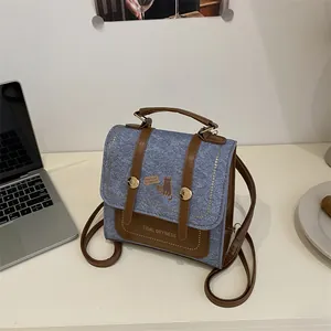 Retro denim backpack with brown leather trim and cat print on a minimalist desk