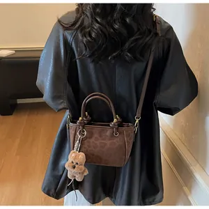 Nahaufnahme der Leoparden-Handtasche mit braunen Ledergriffen und Plüschbär-Anhänger