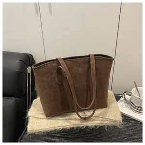 Detailed view of the leopard print texture on a brown suede tote bag with long handles