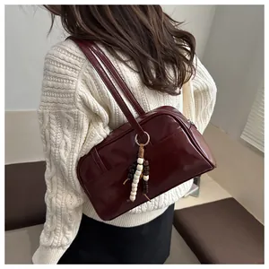 Close-up of deep red glossy shoulder bag with golden ring and beaded pendant detail