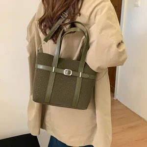 Model wearing dark green wool tote bag with leather strap and silver buckle detail