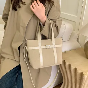 Detail of beige bucket bag featuring belt buckle decor and textured fabric on sofa