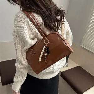 Brown glossy patent leather shoulder bag with beaded charm and shoulder strap