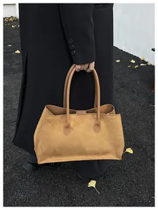 Detail of khaki suede tote bag with leather handles shown in an autumn street setting