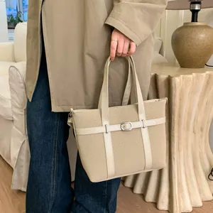 Detail of beige tote bag with silver buckle and leather straps in a lifestyle setting