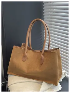 Detailed view of large brown suede tote bag with slim leather handles and matte texture
