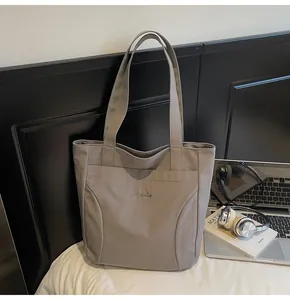 Close-up of minimalist grey canvas tote bag with Midolai embroidery and front pocket