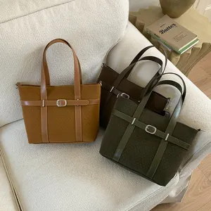 Close-up of vintage bucket bags in brown and olive with decorative belt and buckle detail
