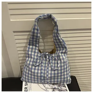 Detail of blue and white checkered canvas tote bag with decorative drawstring bow