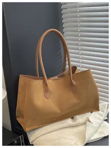 Macro detail of tan suede tote bag texture with slim leather handles in a soft light