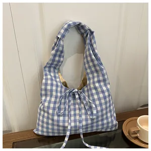 Detail of blue and white checkered tote bag with ribbon bow on a wooden surface