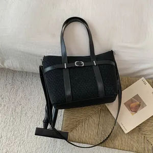 Detail of black textured tote bag with silver metal buckles and adjustable strap