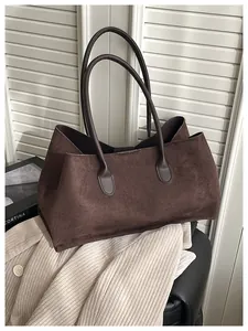 Detail of a large dark brown suede tote bag styled with a neutral blazer for daily commute