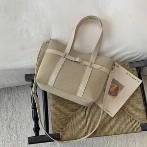 Close-up of beige bucket bag with textured fabric, belt buckle detail and double handles