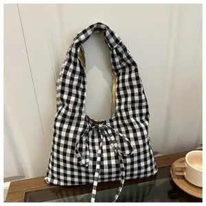 Detail view of black and white checkered fabric handbag with elegant bow decoration