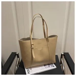 Detail of beige tote bag showing the front pocket design and slim adjustable strap