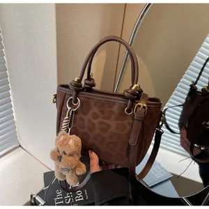 Detail der Leopard-Eimertasche mit Ledergriffen und Plüschbär-Anhänger-Dekor