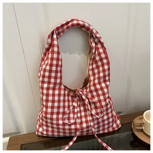 Detail of red and white checkered tote bag with bow decoration on a wooden table