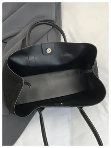 Interior view of black tote bag showing magnetic gold clasp and drawstring closure