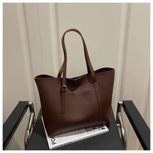 Detail of a large dark brown leather tote bag with a minimalist front pocket design