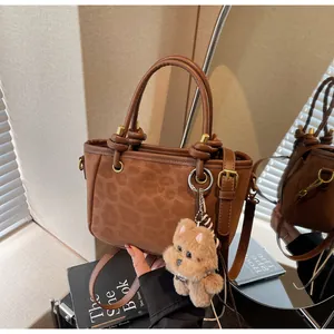 Detail der Handtasche mit Leopardenmuster, Rundgriff und Plüschhund-Anhänger aus Wildleder