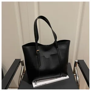 Detail view of large black tote bag on minimalist chair with gold buckle hardware