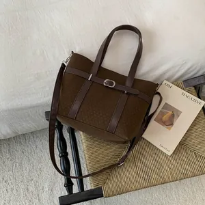 Detail of dark brown wool bucket bag with leather belt buckle in a lifestyle setting