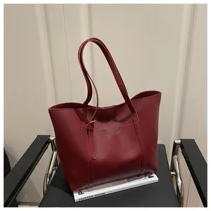 Close-up of deep red leather tote bag with elegant vertical stitching and metal buckles