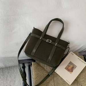 Detailed view of olive green textured bucket bag with leather strap and silver buckle