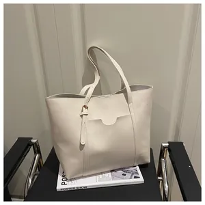 Close-up of cream PU leather tote bag with unique front pocket and gold buckle detail