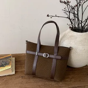Vintage dark brown bucket bag with woven texture and leather strap on wooden surface
