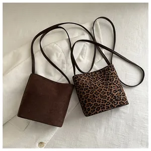 Detailed comparison of brown matte and leopard print mini bucket bags on white fabric