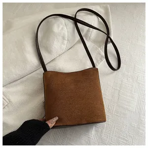 Macro view of caramel brown suede texture and leather strap on a minimalist bucket bag