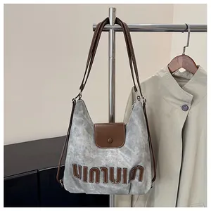 Nahaufnahme der grauen Stofftasche mit Marmortextur, braunem Lederriemen und Logo-Detail