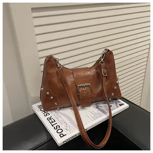 Detail of caramel brown shell bag with silver cone rivets and leather buckle design