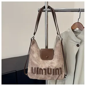Detail einer Vintage-Schultertasche mit großen Buchstaben-Patches und Lederriemen für Damen