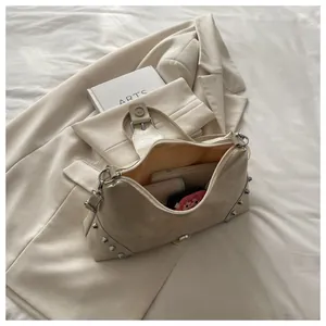 Detail view of cream rivet crossbody bag interior showing phone storage and studs