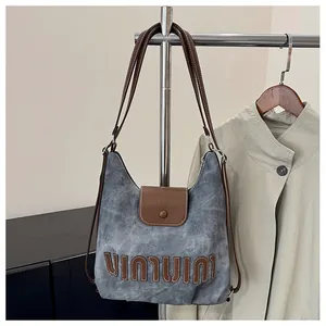 Detail einer Vintage-Handtasche aus grauem Segeltuch mit braunen Lederriemen und Nähten