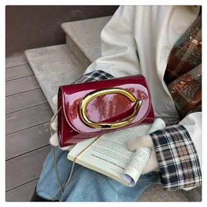 Close-up of wine red patent leather shoulder bag with glossy finish and gold metal buckle