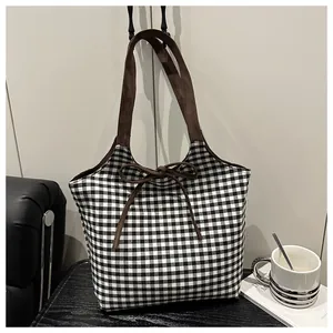 Λεπτομέρεια τσάντας gingham με καφέ σουέτ φιόγκο και υφαντή υφή σε λευκό φόντο