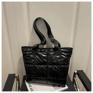 Detail of black quilted tote bag with glossy finish and wide nylon shoulder straps