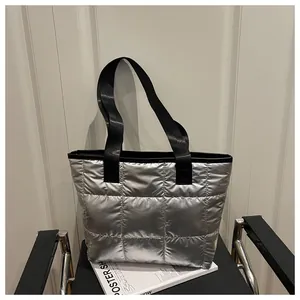 Macro shot of silver quilted tote bag with black strap resting on a magazine and chair